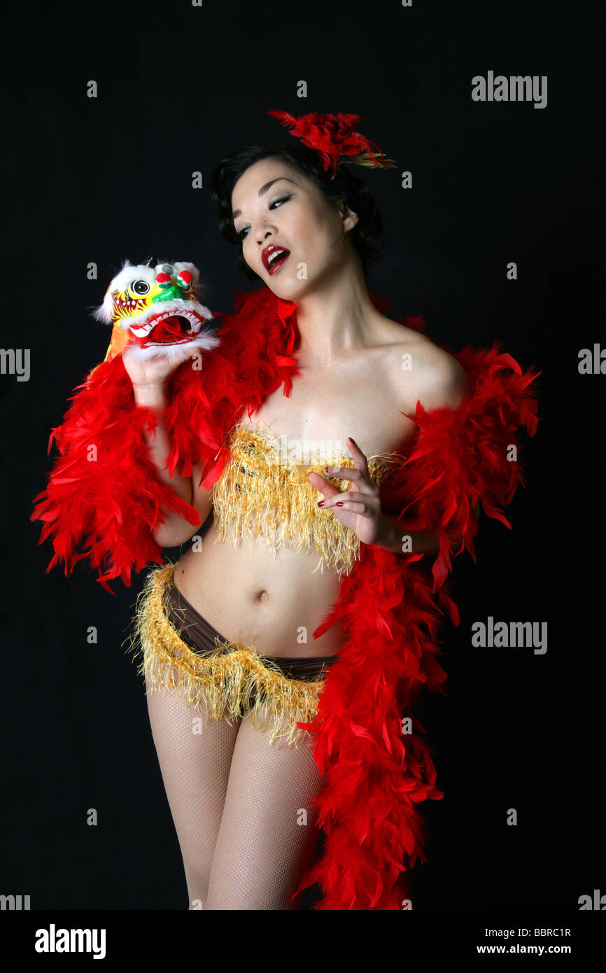 Portrait de l'artiste burlesque pin up Marianne Cheesecake avec Lion Chinois Dragon et Red Feather Boa Banque D'Images