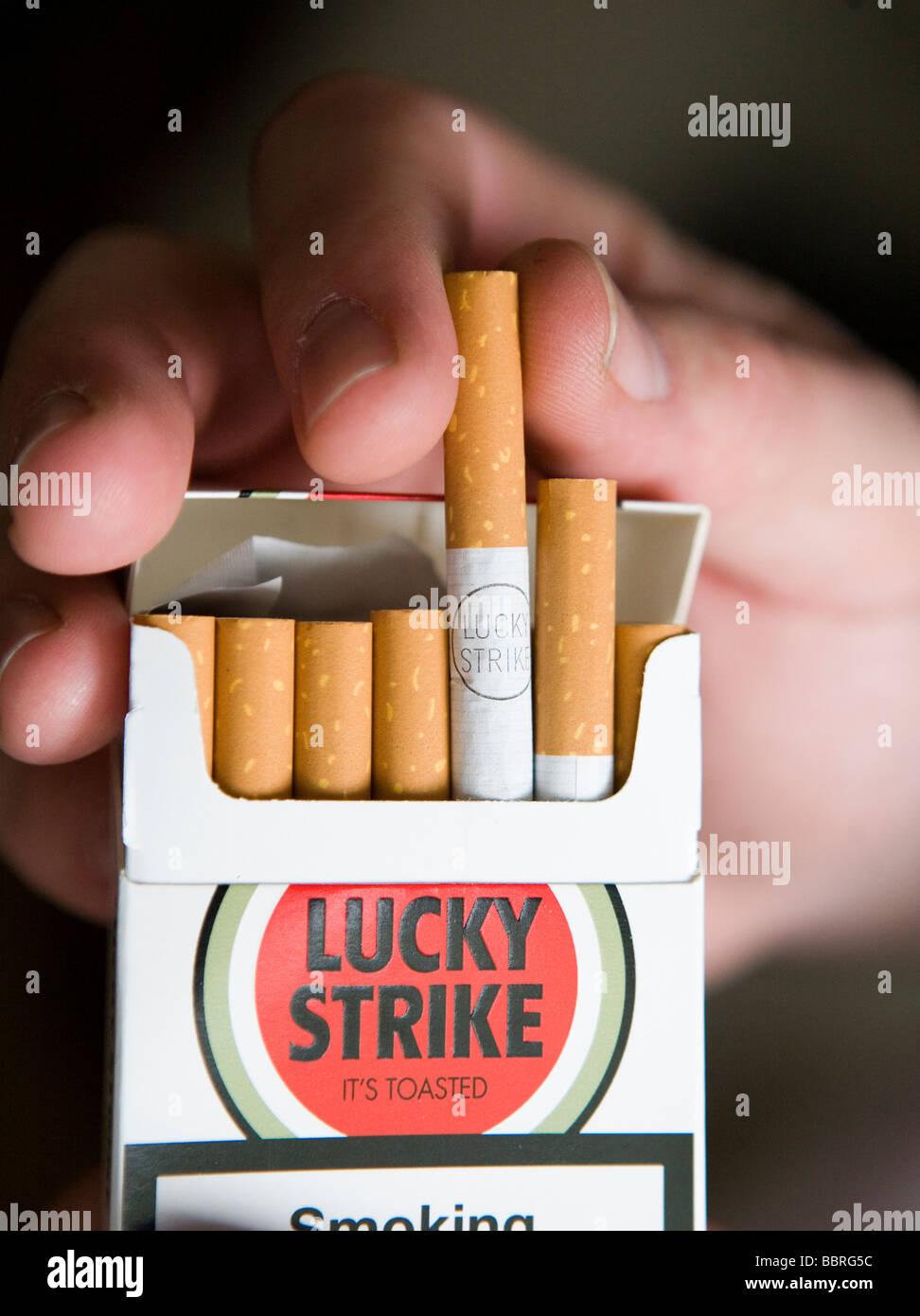 Un fumeur prend une cigarette Lucky Strike faite par British American Tobacco à partir d'un paquet Banque D'Images