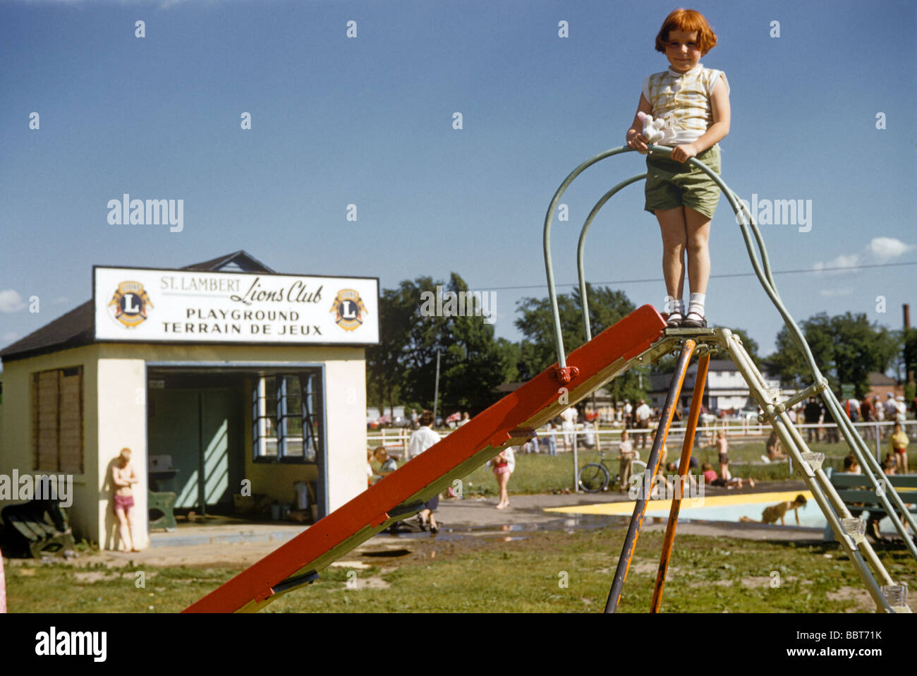 Petite fille en haut d'une diapositive dans les jeux pour enfants 1957 Banque D'Images