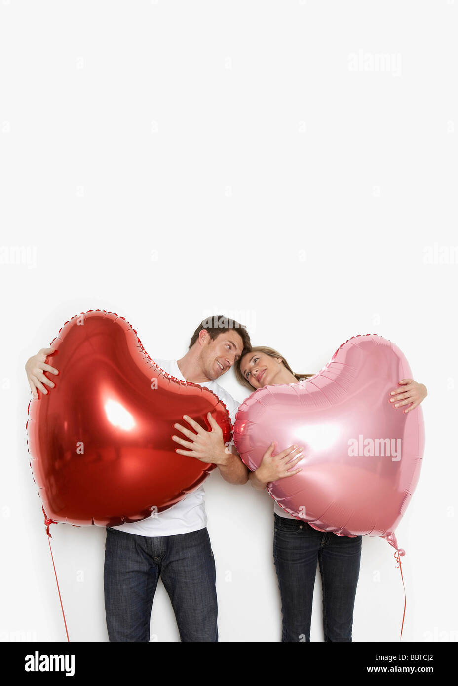 Couple holding heart balloons Banque D'Images