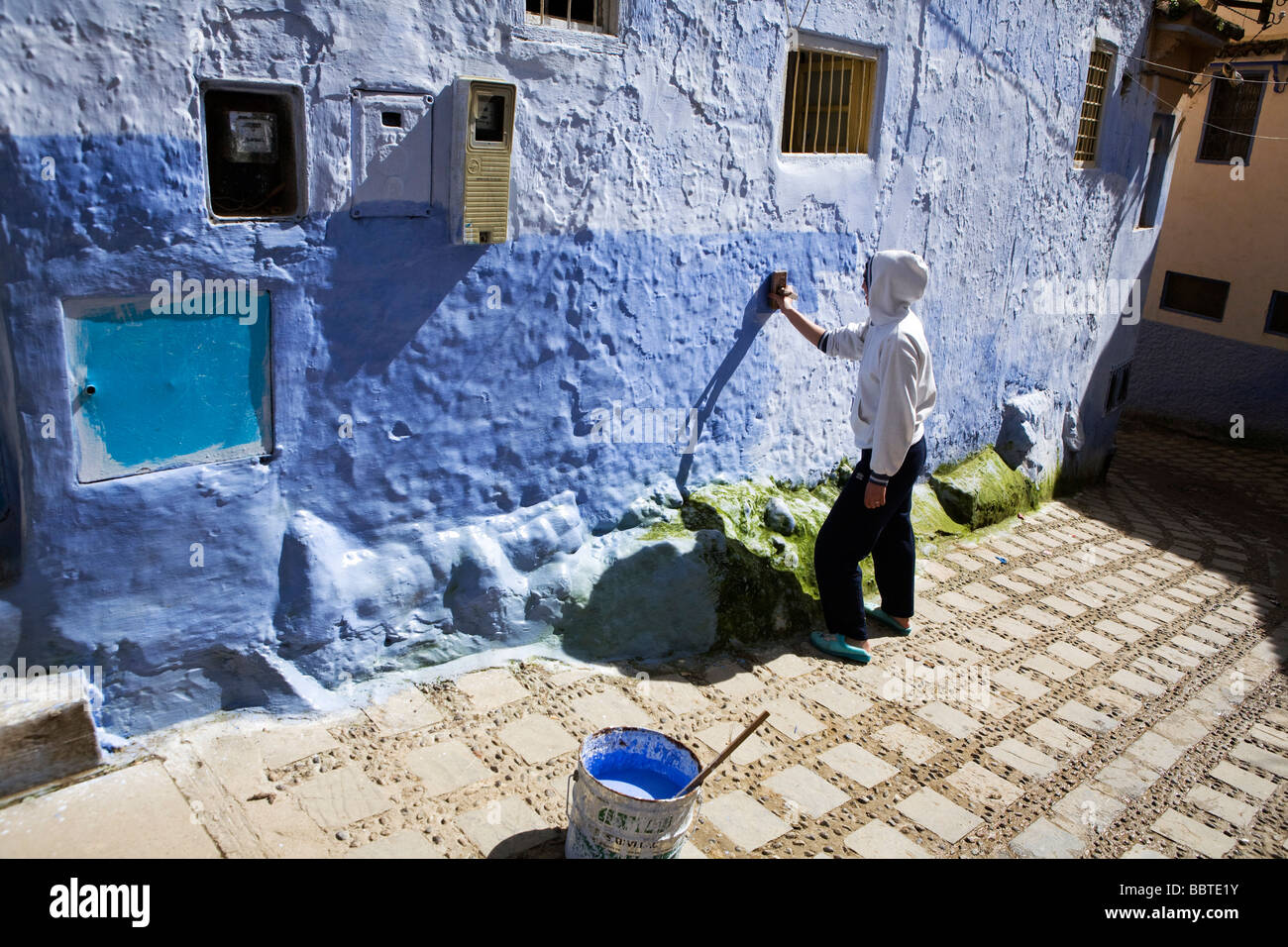 Fille peinture des murs avec de la peinture bleue dans la médina, Chefchaouen, Maroc, Afrique du Nord Banque D'Images