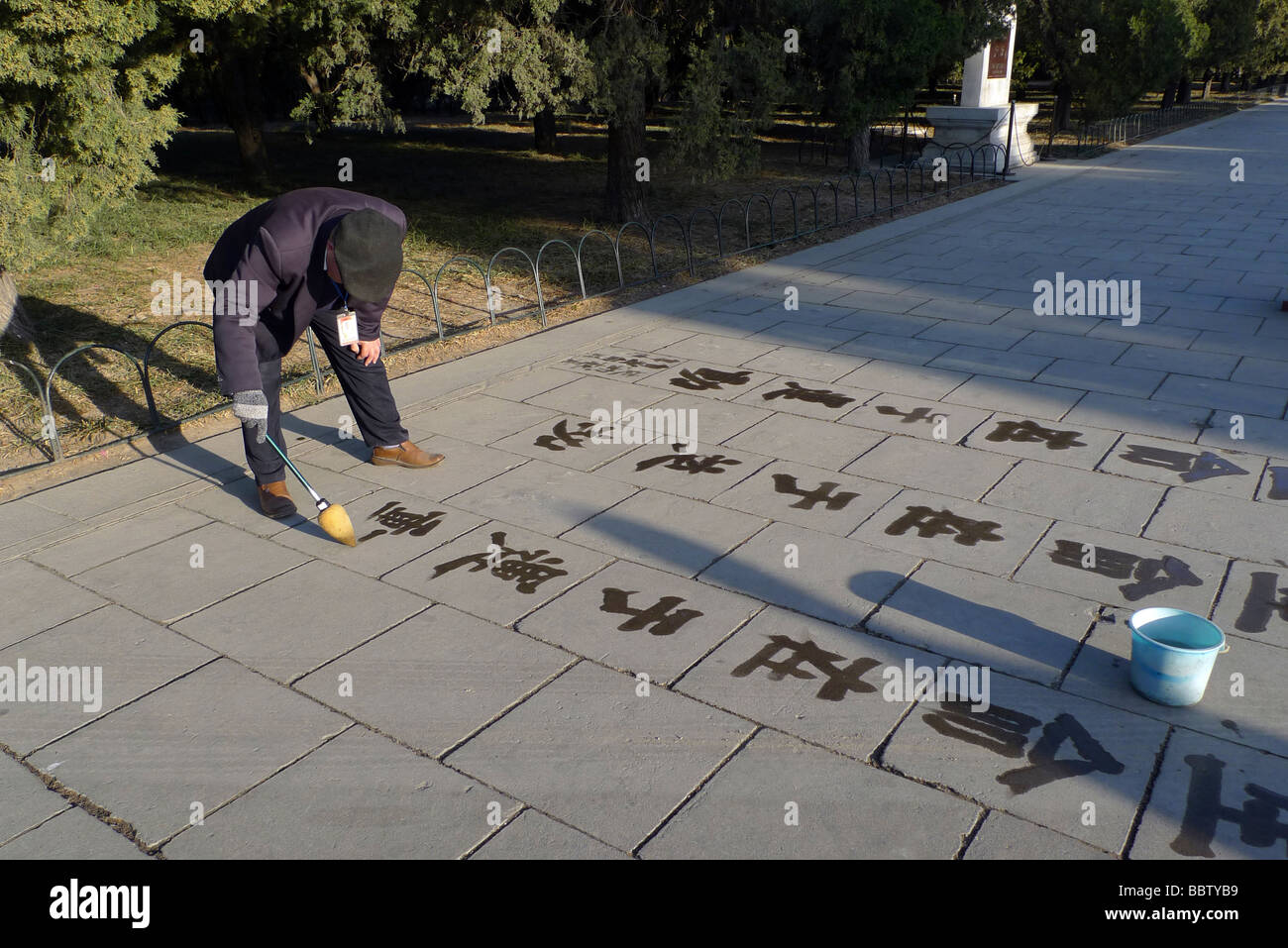 Vieux chinois pratiquant sa calligraphie dans Tian Tan park, Beijing, Chine. Banque D'Images