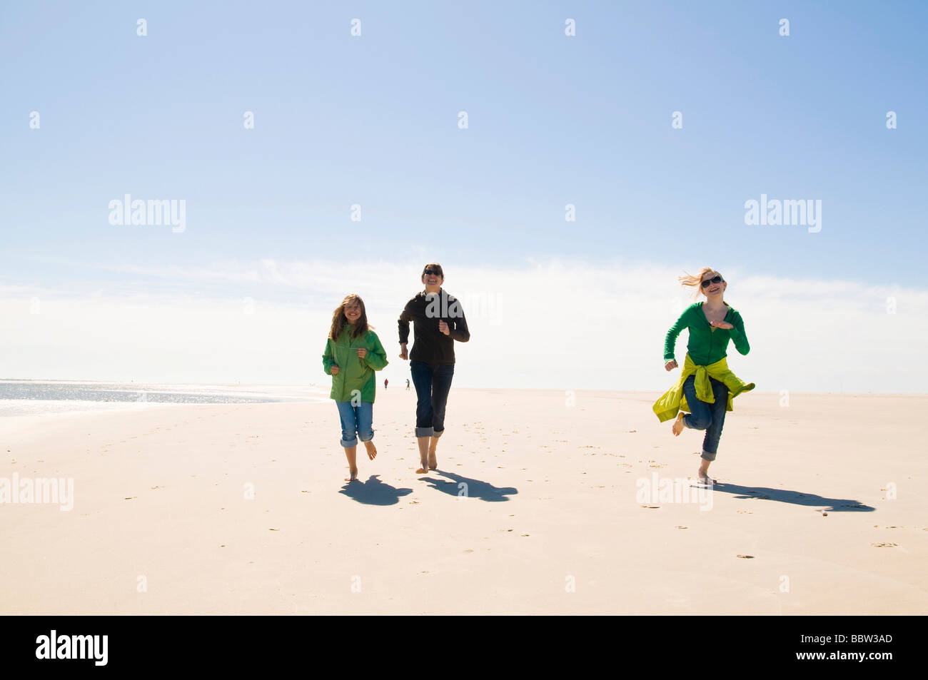 Jeune femme et deux jeunes gens d'exécution et de rire sur la plage, Amrum, Mer du Nord, l'Allemagne, de l'Europe Banque D'Images