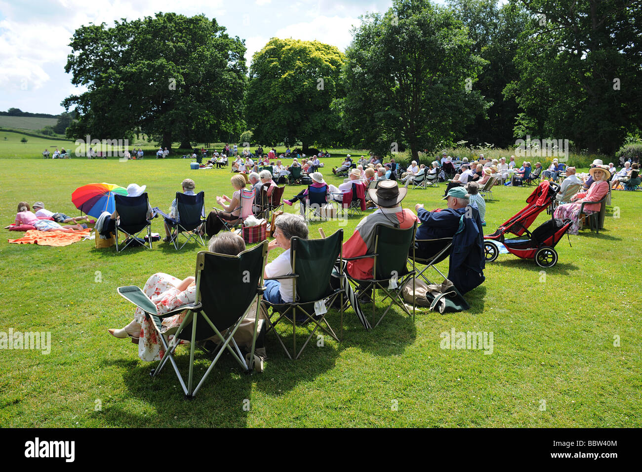 Foule audience avec pique-nique sur une pelouse, à l'ouest de l'Angleterre l'Angleterre dans le soleil de l'été Banque D'Images