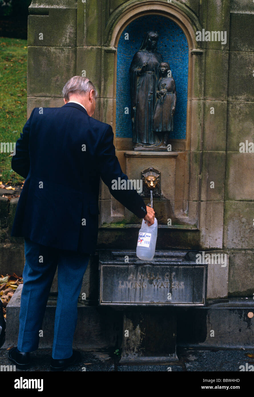 Un vieux passant local s'arrête à réapprovisionner gratuitement sa bouteille d'un parc naturel au printemps dans le centre-ville de Buxton Banque D'Images