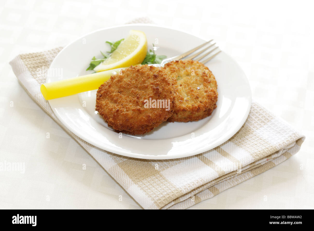 La morue panés délicieux fraîchement préparés Fishcakes avec citron et garnir de feuilles de salade isolé sur un fond blanc avec aucun peuple et un chemin de détourage Banque D'Images