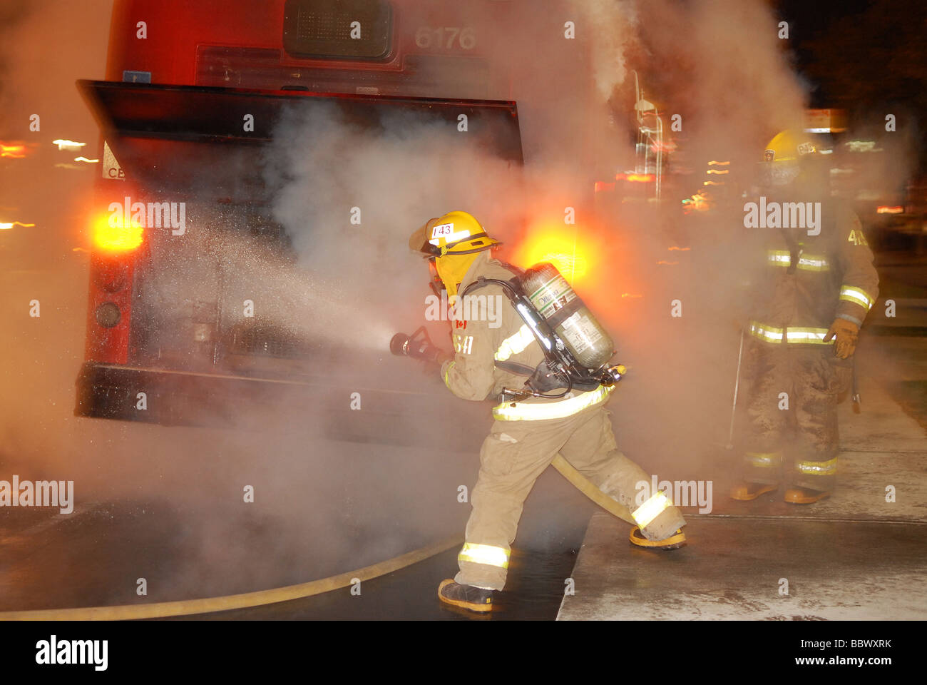 Les équipes d'incendie pulvériser de l'eau sur un incendie moteur dans un bus. Banque D'Images