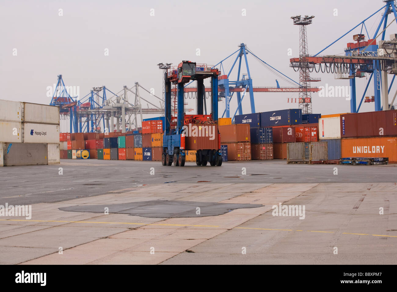 Un camion transporteur de chevauchement se déplace autour de conteneurs ISO de terminal des conteneurs pour être empilés et traitées. Banque D'Images