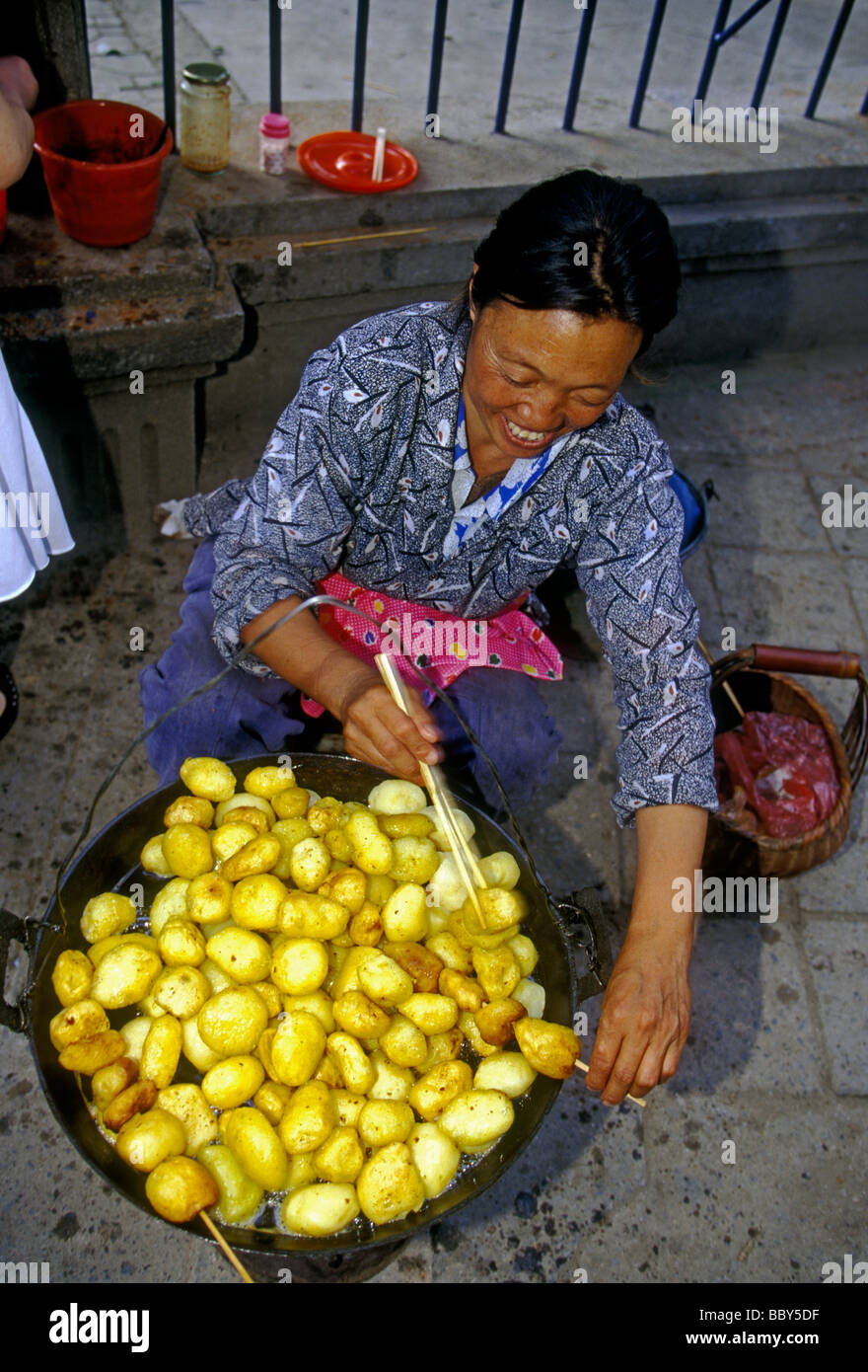 1, l'un, femme chinoise, femme adulte, de l'alimentation, de l'alimentation du vendeur vendeur, vendeur de rue, la vente des pommes de terre sautées, frites, Kunming, Province du Yunnan, Chine Banque D'Images