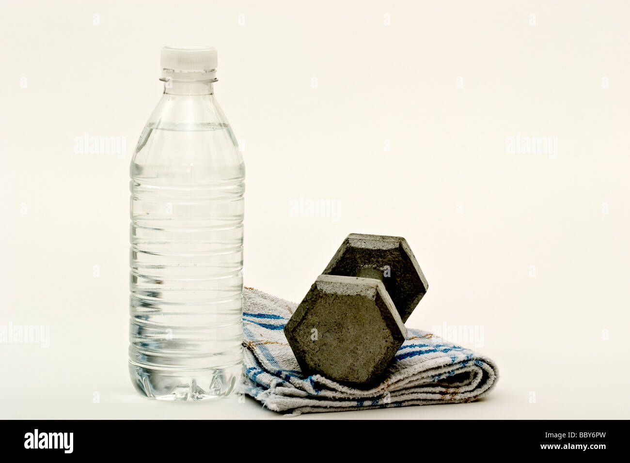 Un haltère sur une serviette de sueur à côté d'une bouteille d'eau Banque D'Images