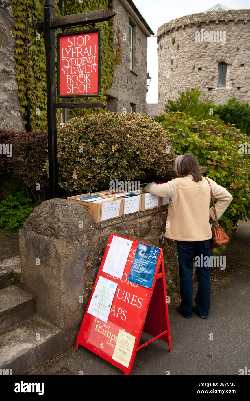 Une femme parcourt des boîtes de livres à l'extérieur d'une librairie de seconde main à St Davids, Pembrokeshire Wales UK Banque D'Images
