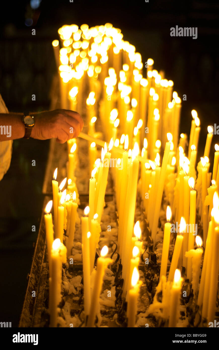 L'éclairage de l'homme à l'église votive candle Banque D'Images