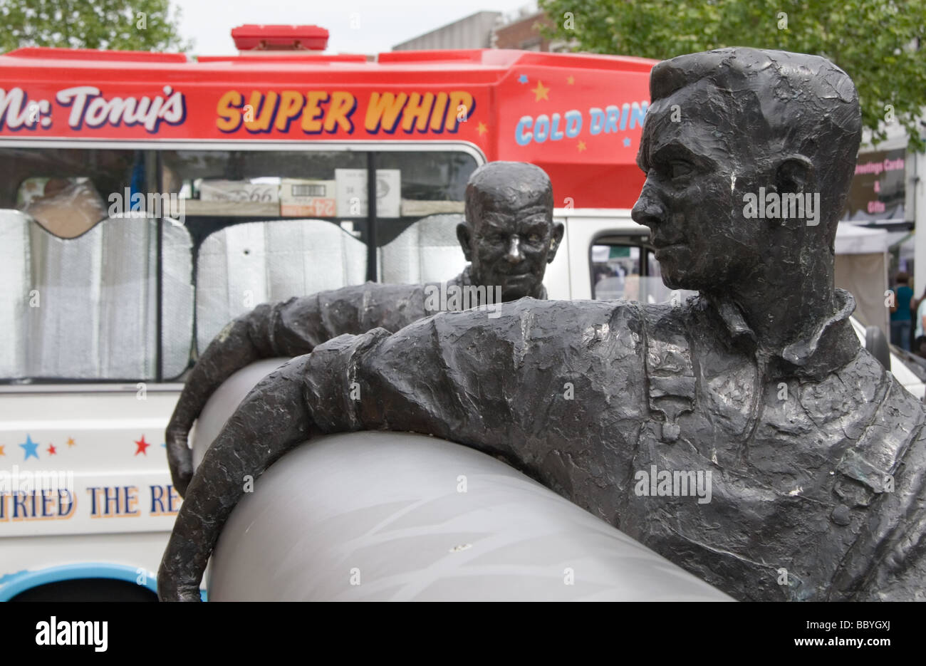 Sculpture de deux hommes portant un rouleau de lino, avec une glace van dans l'arrière-plan : Staines, Middlesex. Banque D'Images