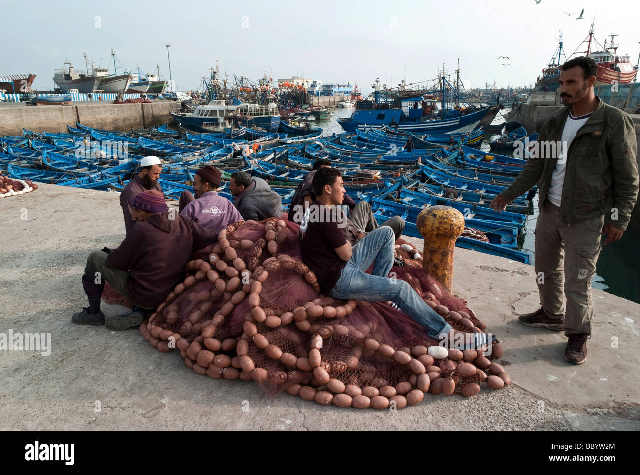 Les pêcheurs assis sur les filets de pêche dans le port, Essaouira, Maroc, Afrique Banque D'Images