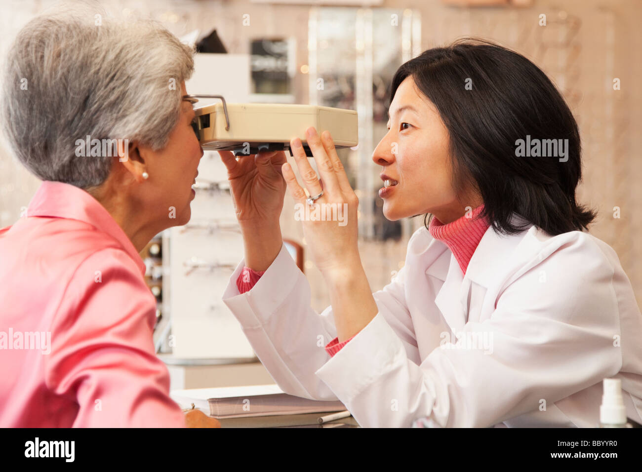 Korean optician giving woman eye exam Banque D'Images