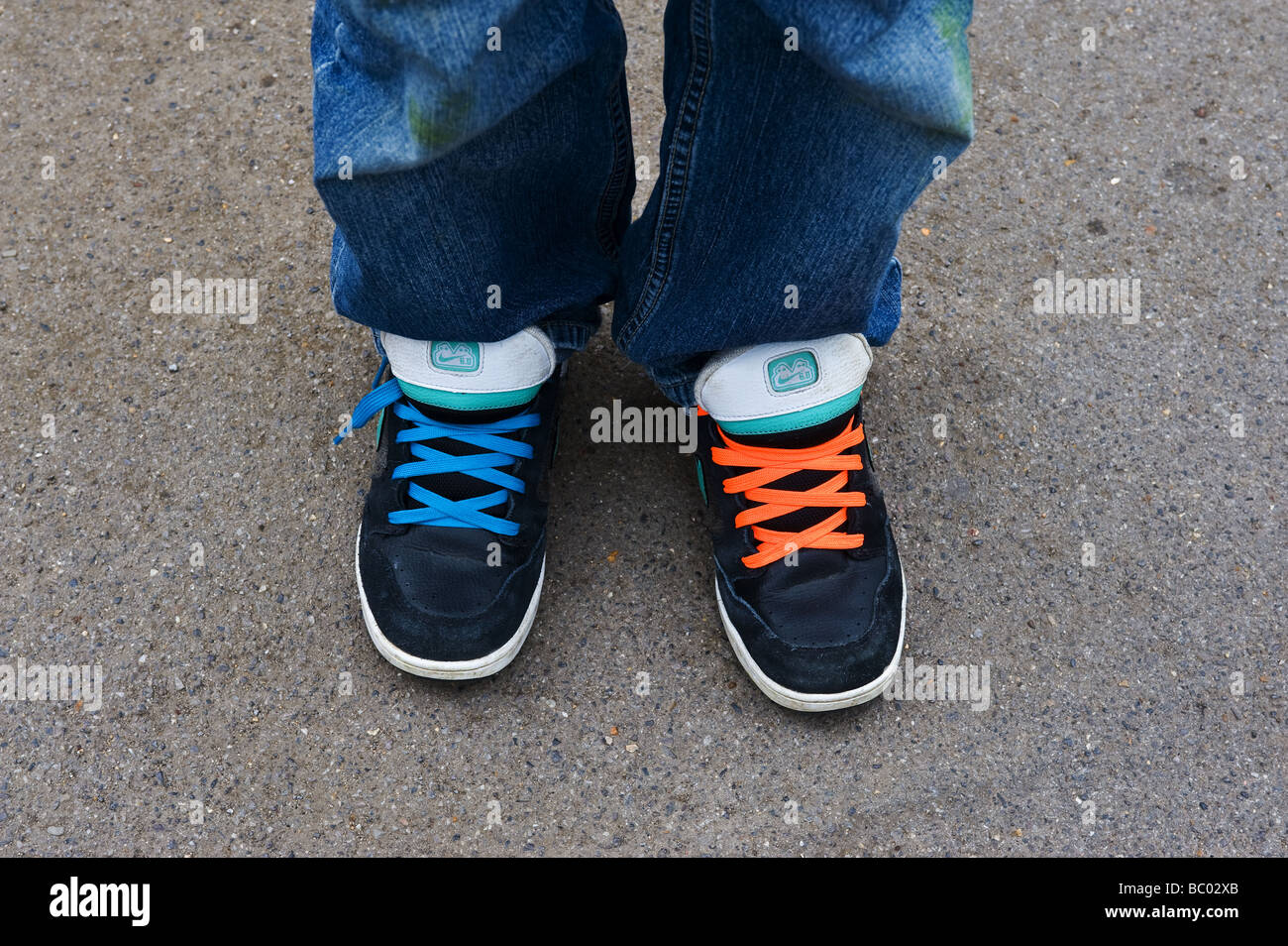 Une personne portant des chaussures de formateurs avec différentes couleurs de lacets. Photo par Gordon 1928 Banque D'Images