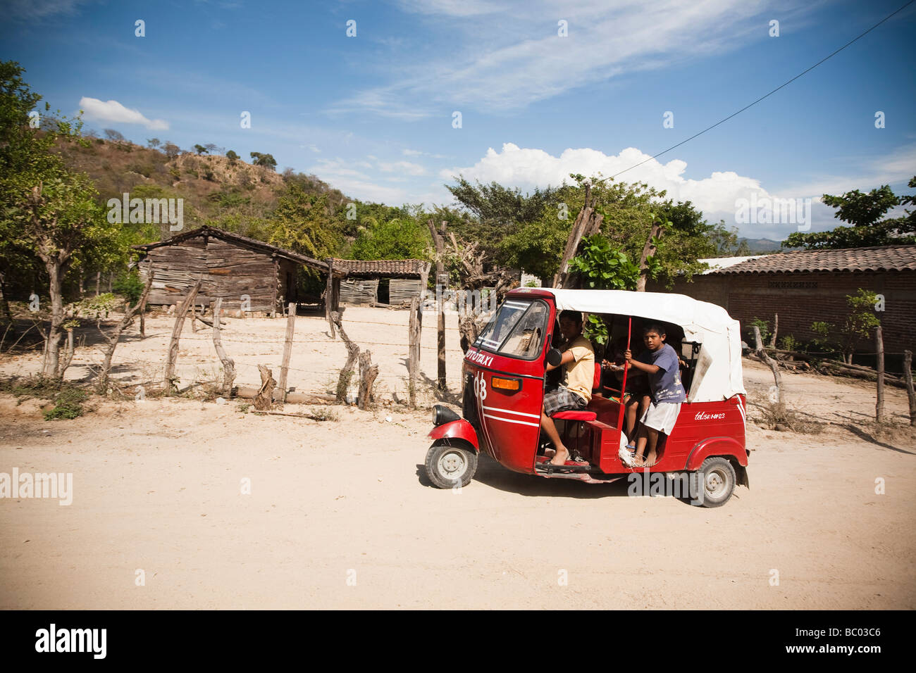 Un mototaxi conduit certains enfants au moyen d'une route non asphaltée dans une communauté à Oaxaca, au Mexique. Banque D'Images