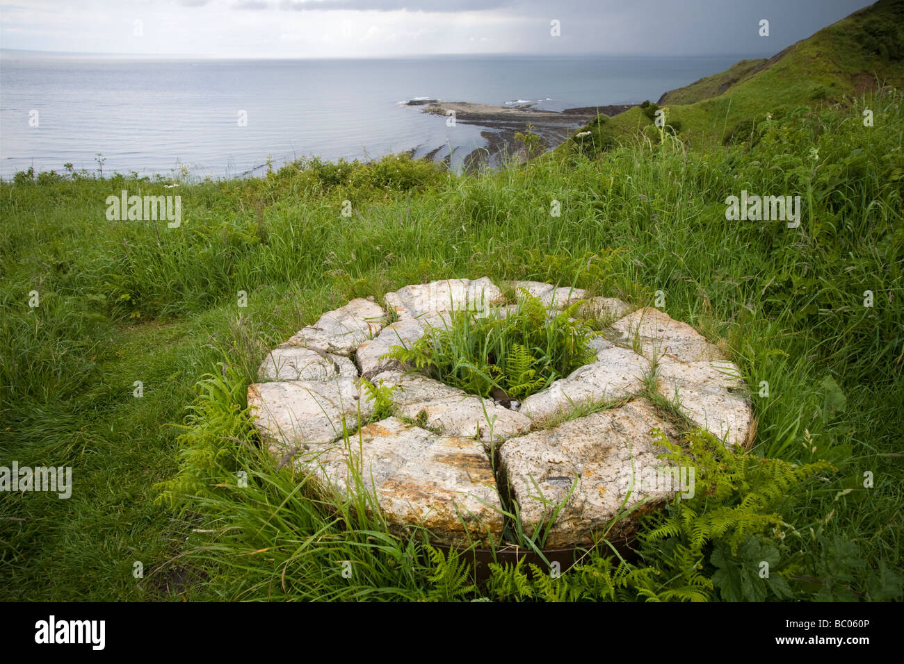 Restes d'une meule en pierre de la pointe de l'Alun fonctionne avec Cliff et dans la mer du Nord Yorkshire Angleterre distance Ravenscar Banque D'Images