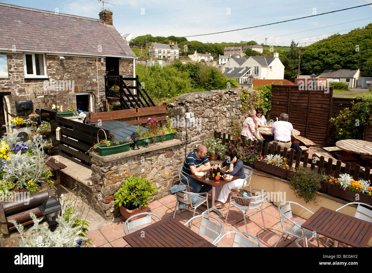 Les gens assis à l'extérieur d'un pub sur un après-midi d'été peu Haven south Pembrokeshire Coast National Park West Wales UK Banque D'Images