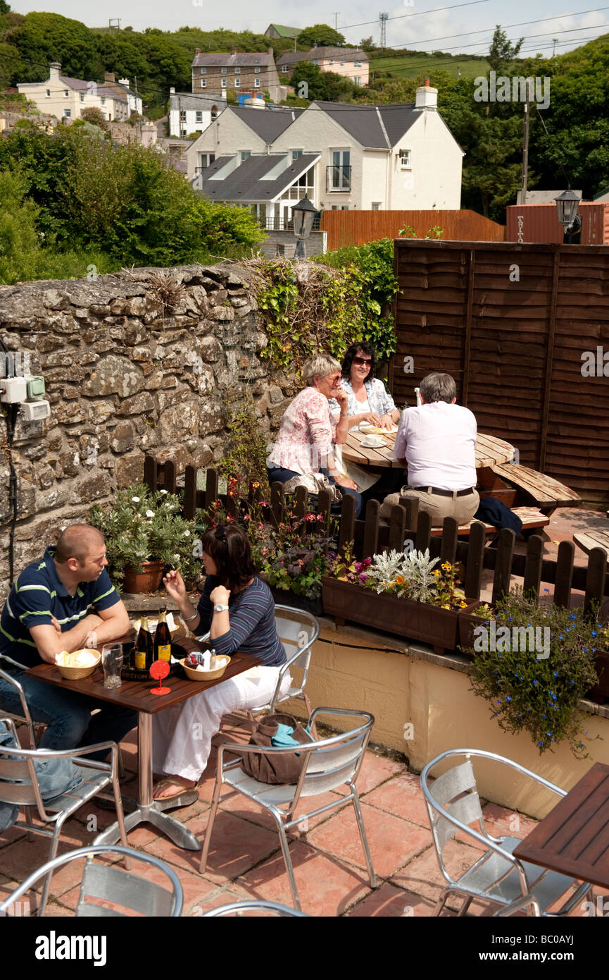 Les gens assis à l'extérieur d'un pub sur un après-midi d'été peu Haven south Pembrokeshire Coast National Park West Wales UK Banque D'Images