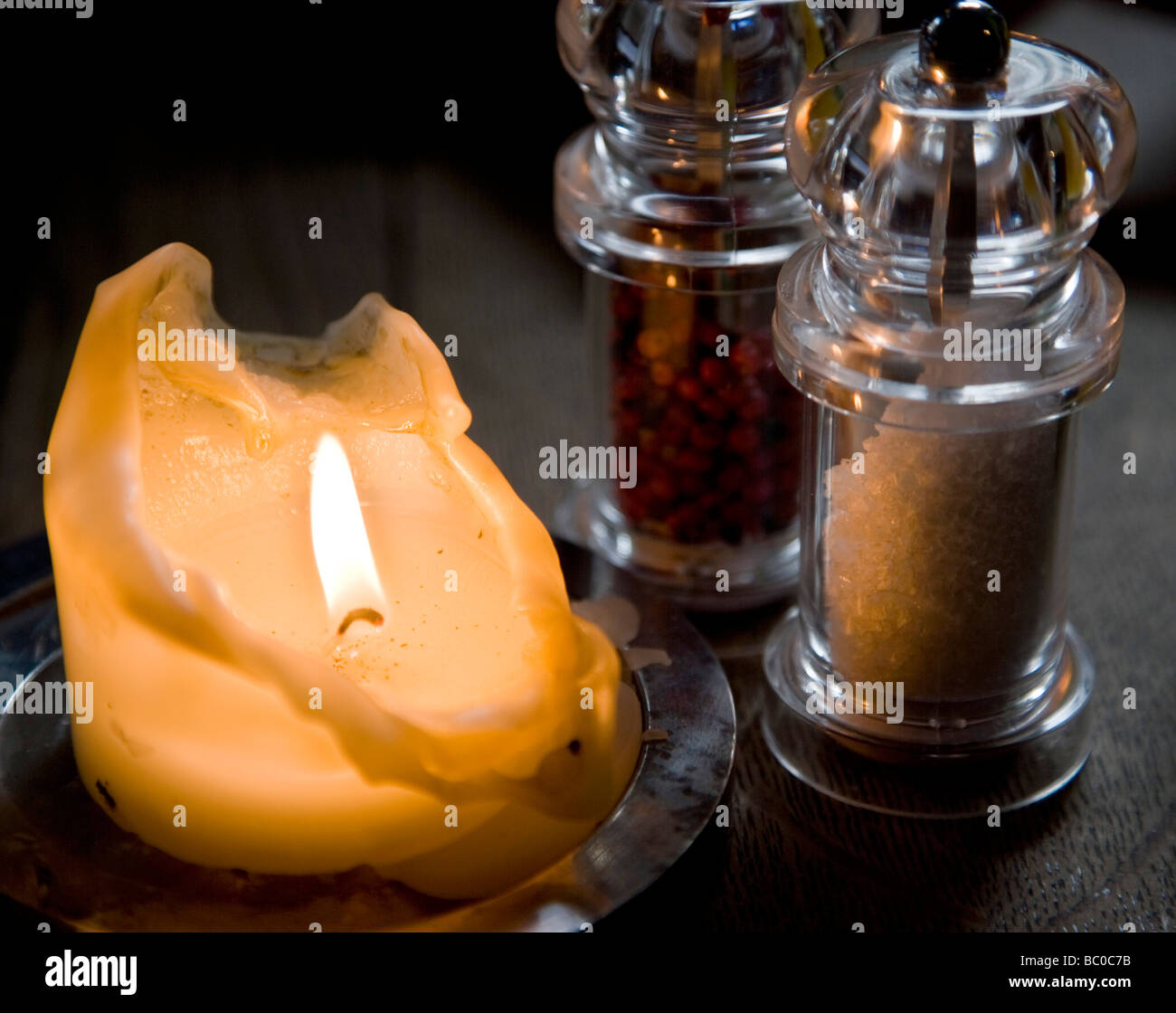 Candle Burning en lumière tamisée par le sel et moulins à poivre Banque D'Images