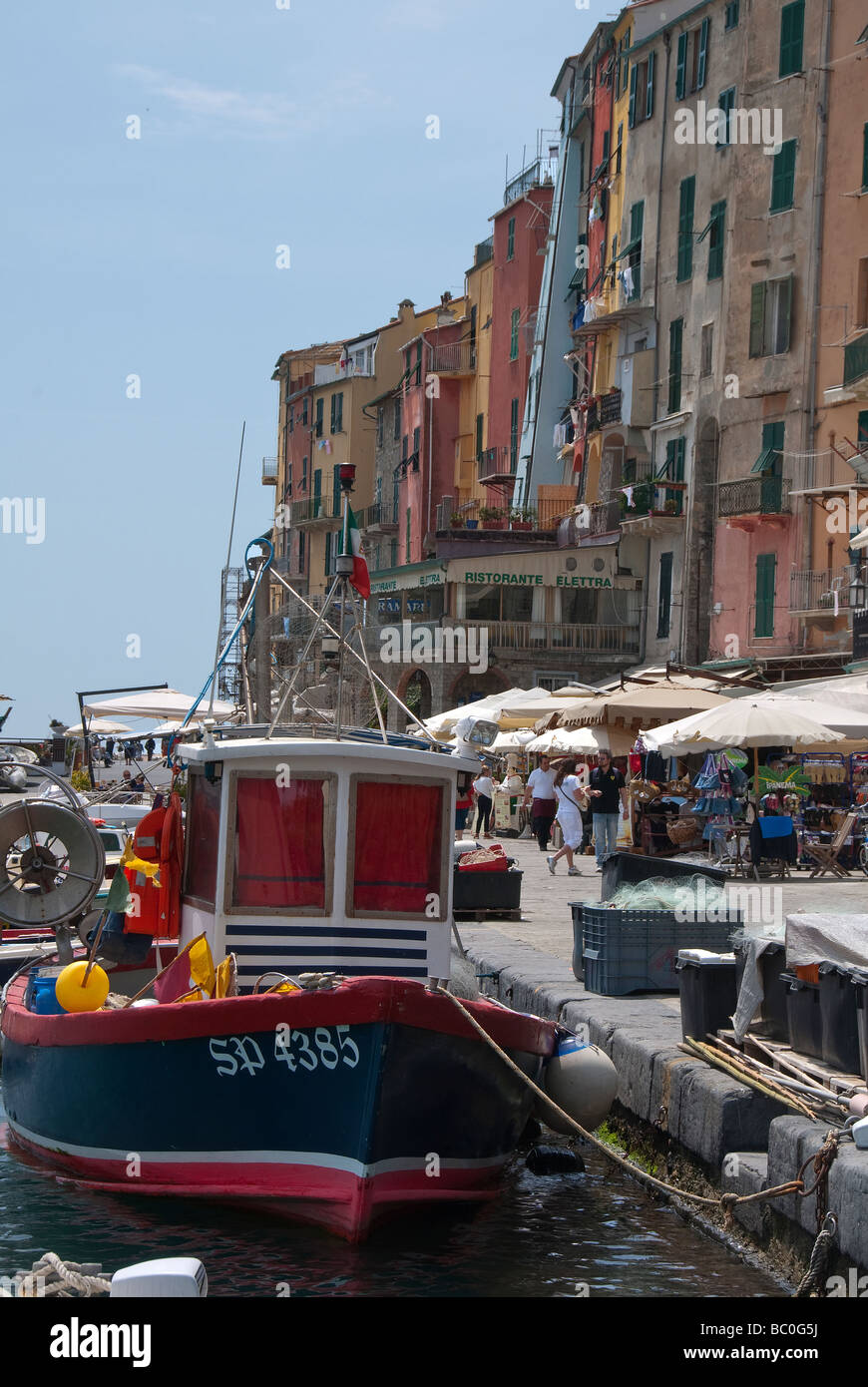 Bateau de pêche amarré au quai de Porto Venere avec restaurants quai et parasols Banque D'Images