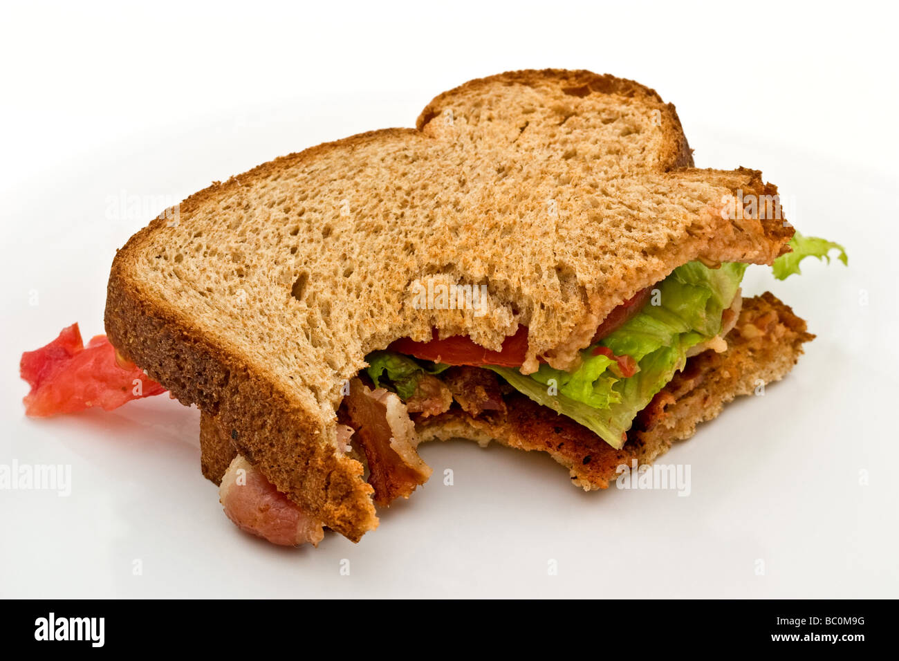 Bacon, laitue et tomate sandwich sur pain brun avec une morsure pris hors de lui Banque D'Images