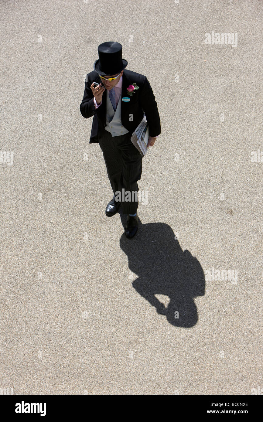 Un Royal Ascot race goer arrive à la réunion jette une ombre dans la lumière du soleil forte Banque D'Images