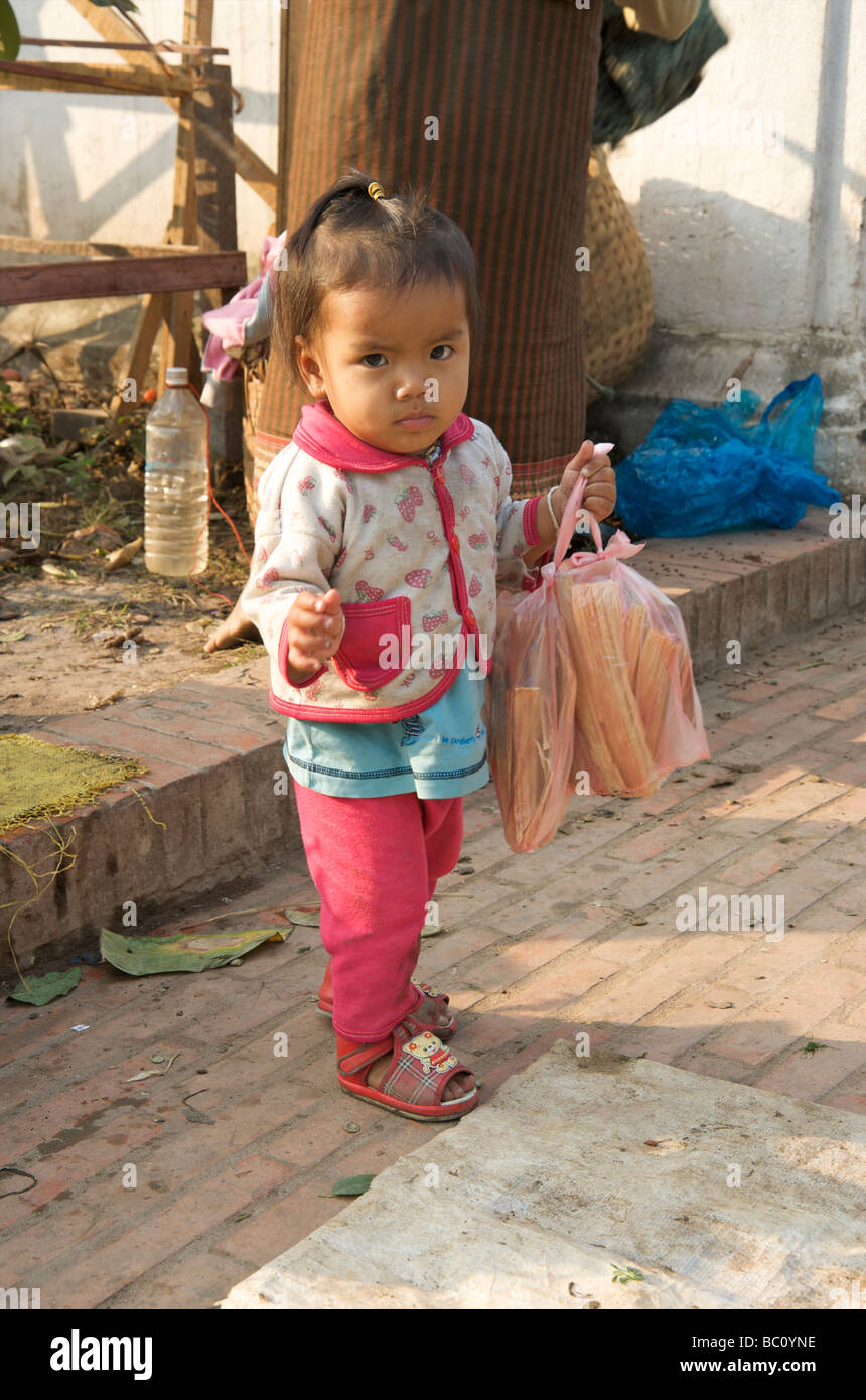 Un bébé d'ajo se tient derrière sa mère, food à Luang Prabang au Laos Banque D'Images
