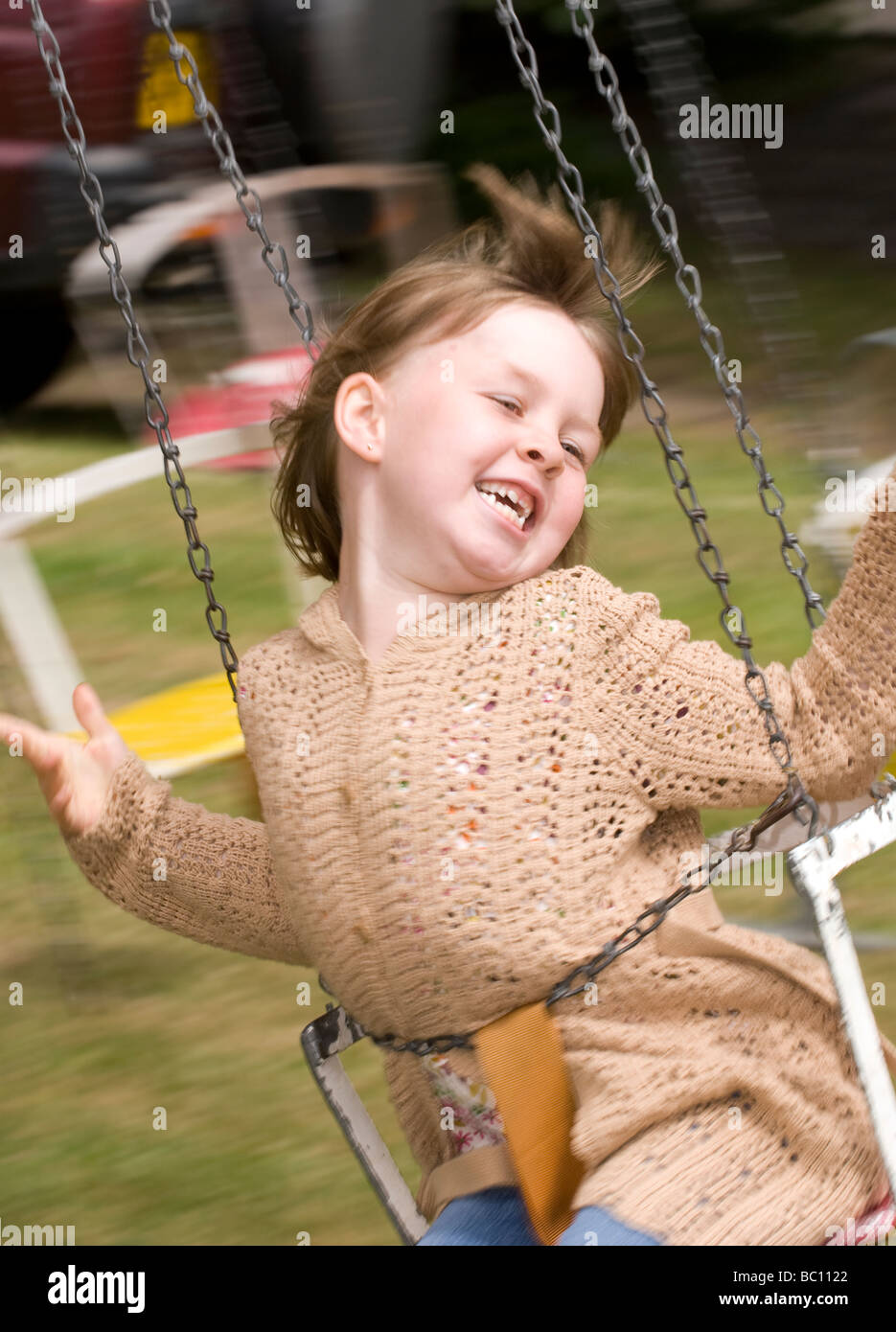 6 ans, fille, s'amusant sur une balançoire à une école summer fete Runfold, Surrey, UK. Banque D'Images