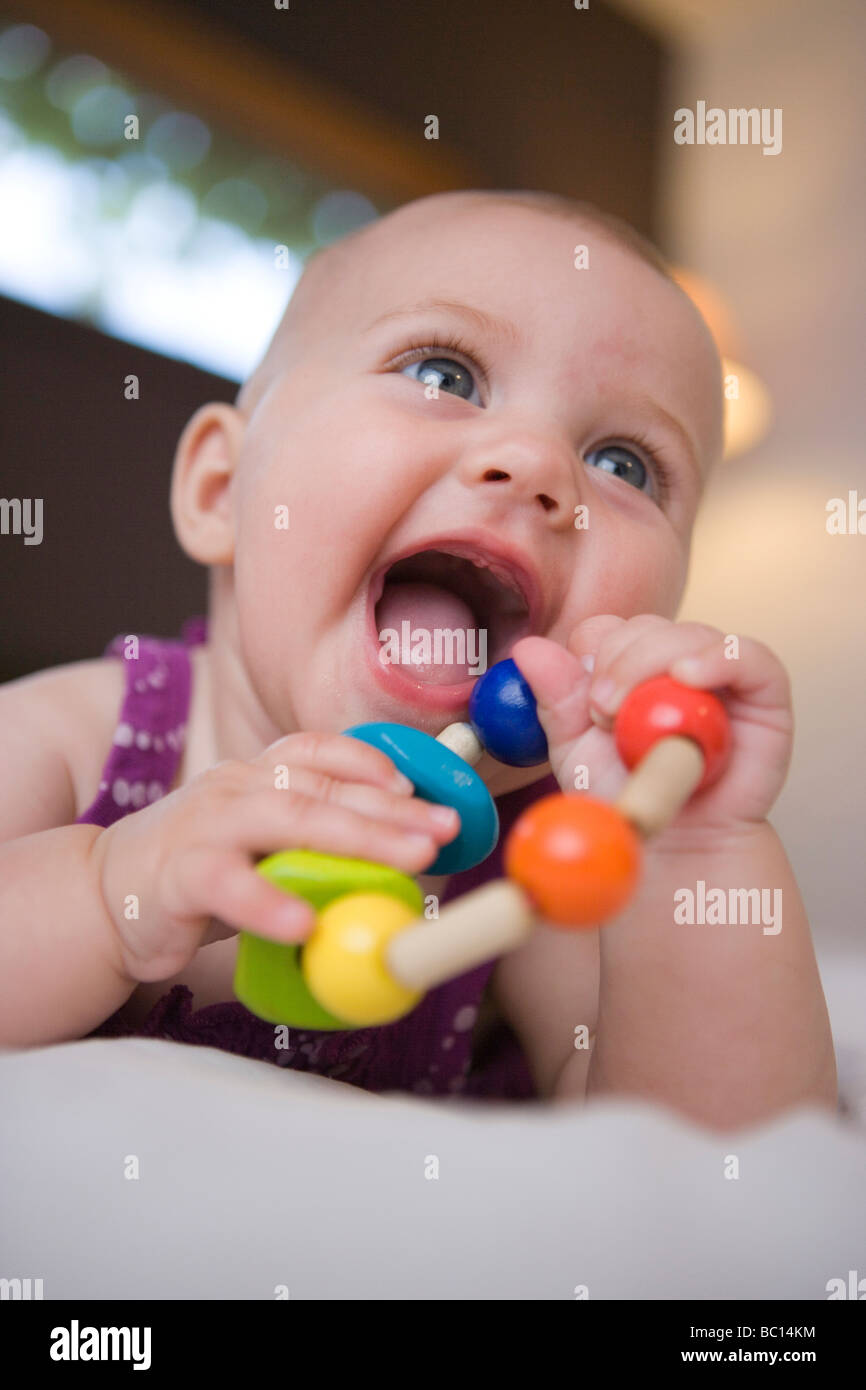 Baby Girl smiling, un jouet de dentition en bois avec la bouche grande ouverte Banque D'Images
