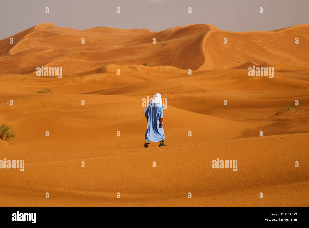 Un homme en costume traditionnel berbère promenades à travers les dunes de l'Erg Chebi désert près de Merzouga Maroc Afrique du Nord Banque D'Images