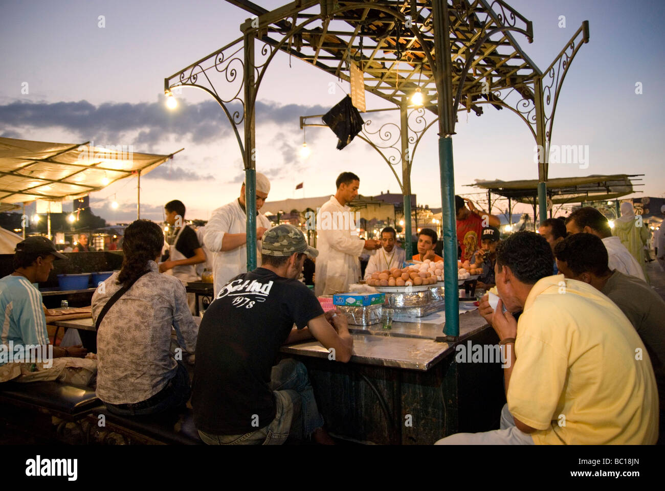 Les gens mangent le souper d'une échoppe de marché au crépuscule sur la place Djema El Fna Marrakech Maroc Banque D'Images