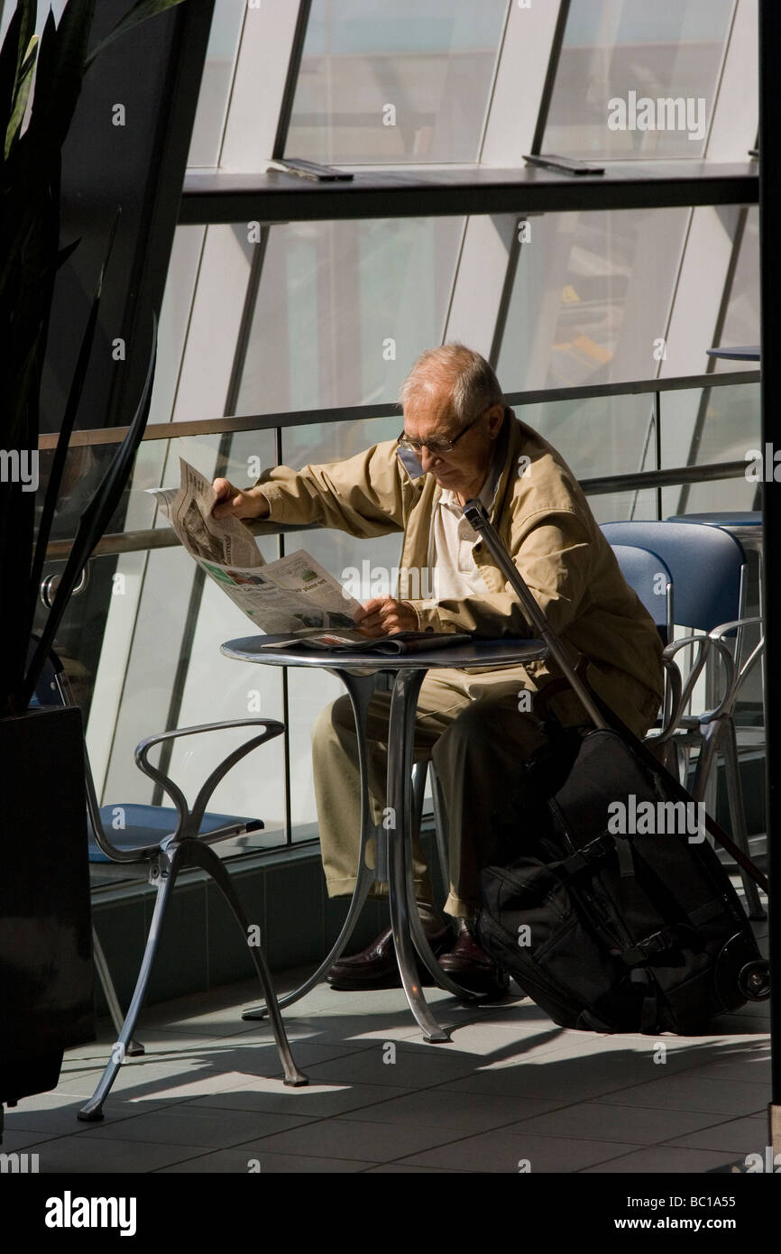 Personnes âgées traveler reading newspaper in airport par fenêtre Banque D'Images