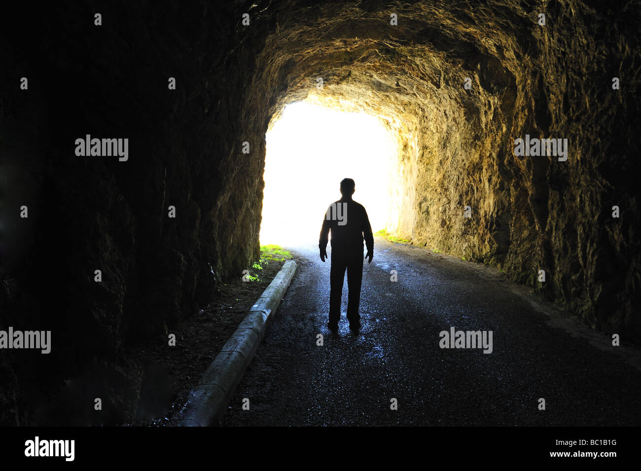 La lumière au bout du tunnel. Silhouette d'une figure debout à la fin d'un tunnel sombre à la recherche dans la lumière du jour. Banque D'Images