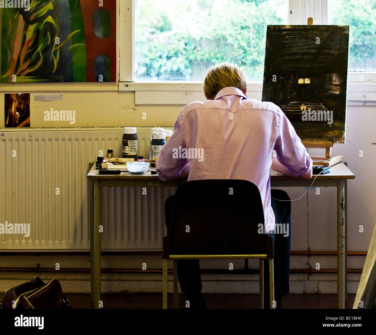 Un étudiant à l'école assis à une table dans un studio d'art de l'école. Banque D'Images