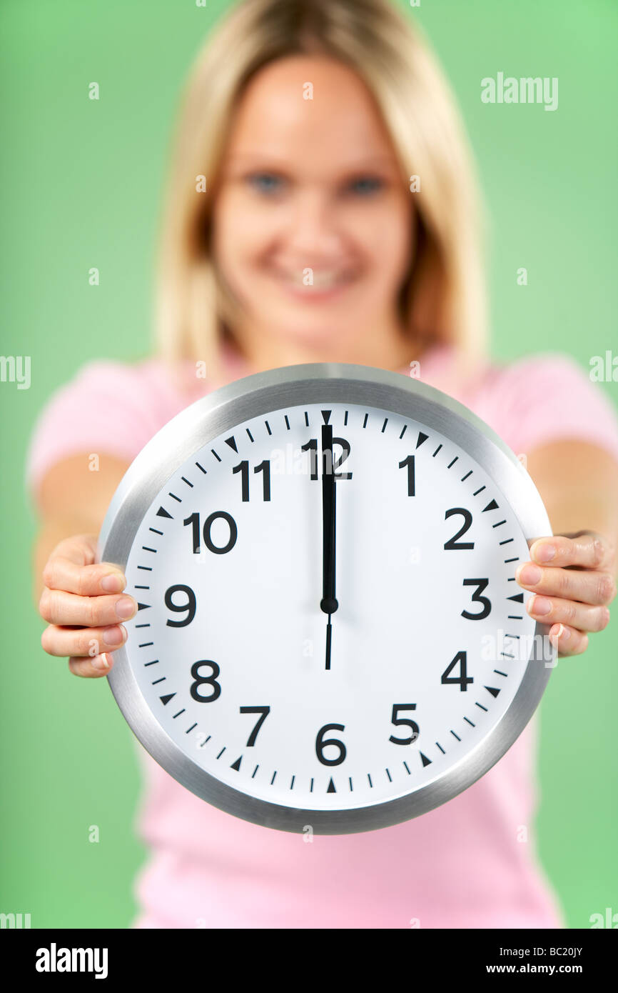 Woman Holding horloge indiquant 12 HEURES Banque D'Images