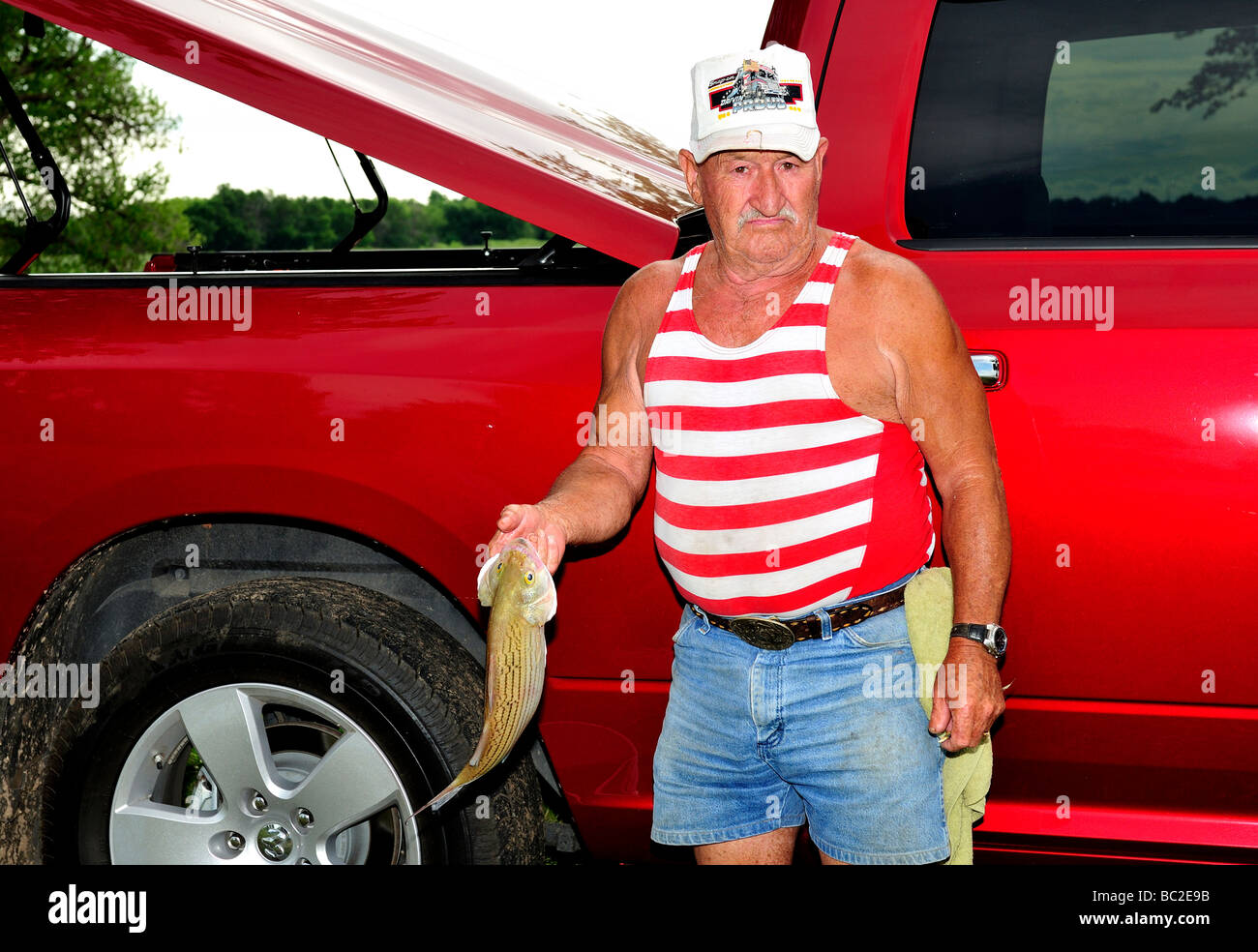 Un 80 ans caucasien homme pose avec un poisson qu'il a capturé dans l'Oklahoma, USA. Banque D'Images