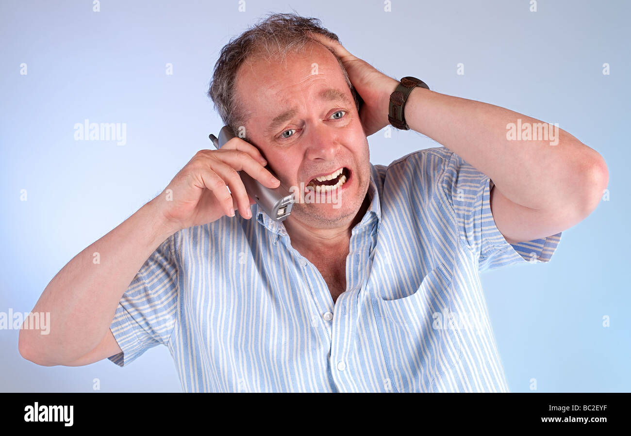 Un homme d'âge moyen est en colère après avoir reçu de très mauvaises nouvelles au téléphone Banque D'Images