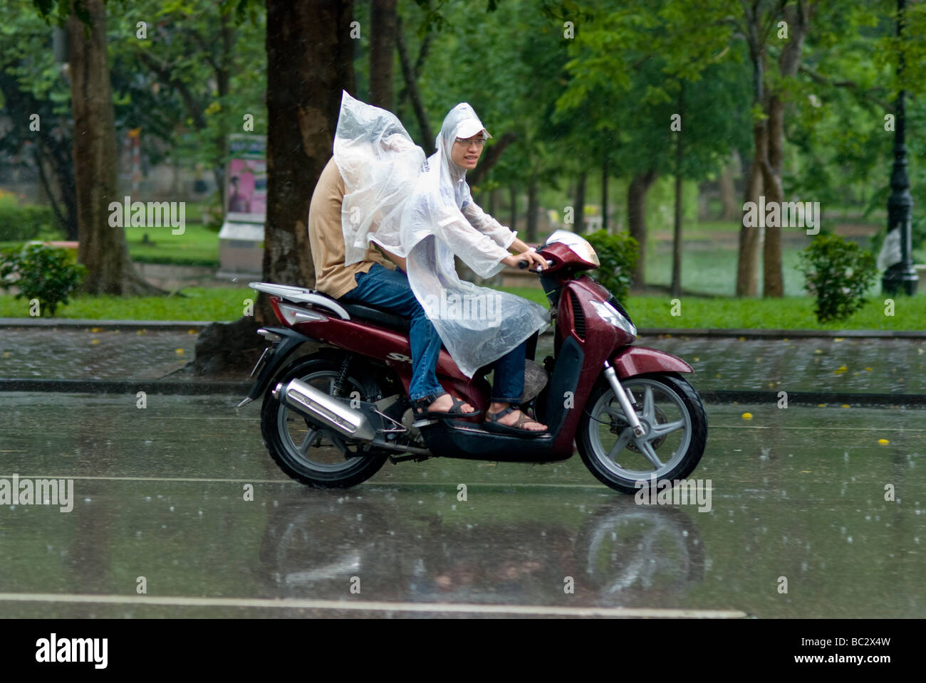 Deux personnes sur une moto sous la pluie à Hanoi Vietnam Banque D'Images