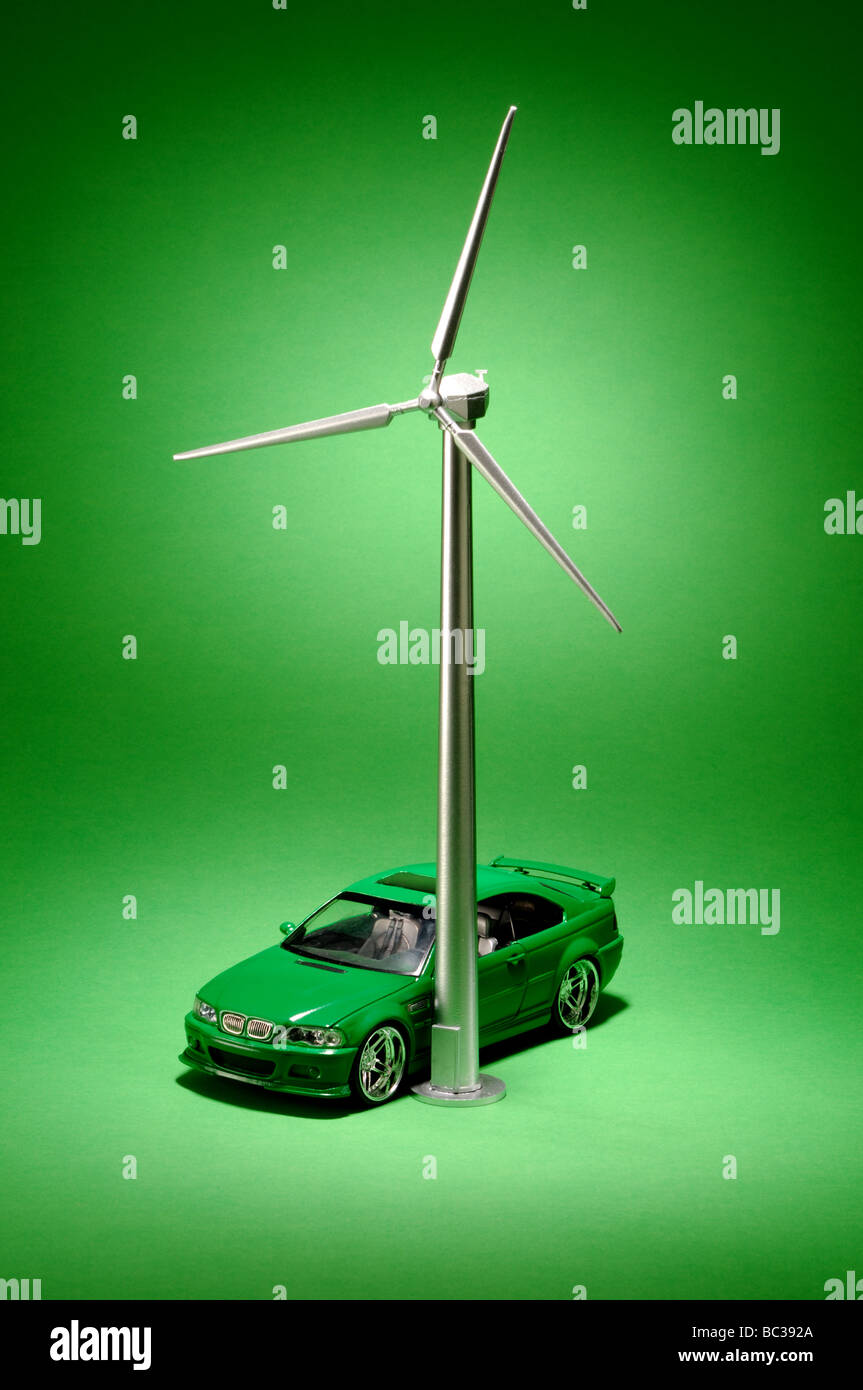 Une petite éolienne de métal sur un fond vert avec une petite voiture grren Banque D'Images