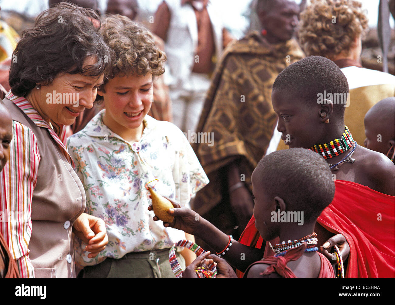 White caucasian mother and daughter traditionnelle réunion enfants massaïs au Kenya Afrique de l'Est vente gourd Banque D'Images