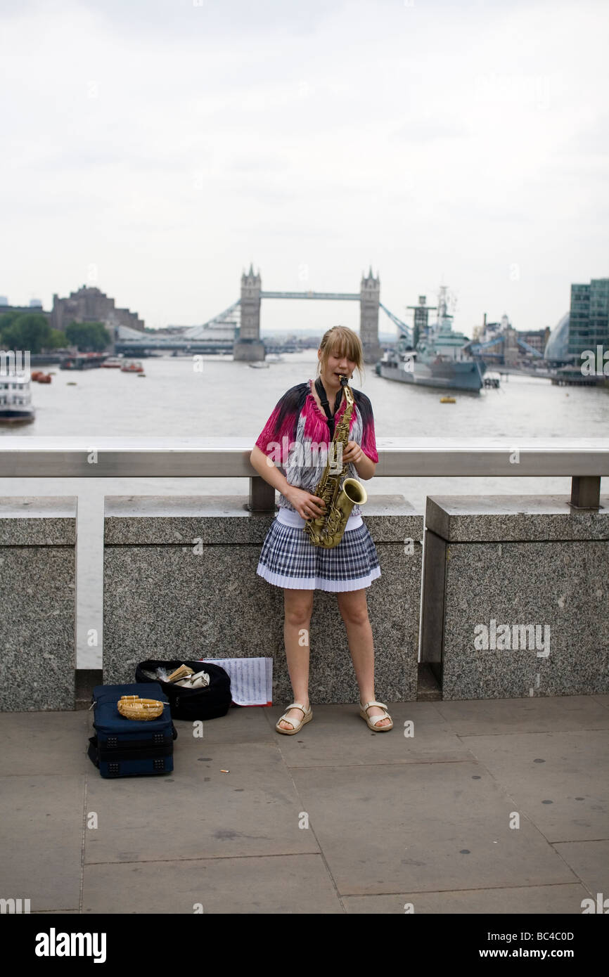 Une femme joue du saxophone sur le pont de Londres. Banque D'Images