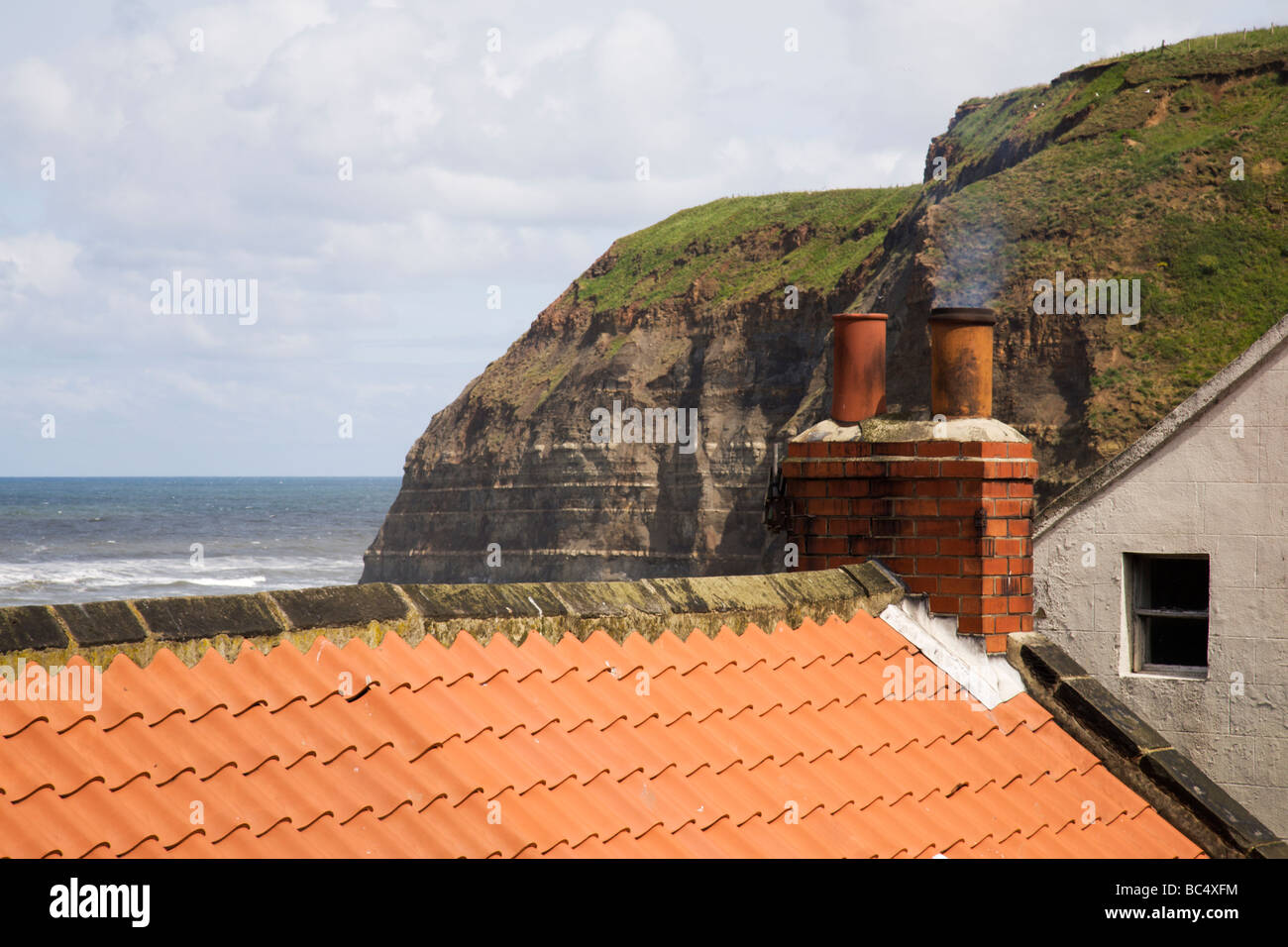 La fumée d'une cheminée chalet pot, donnant sur la mer. Banque D'Images