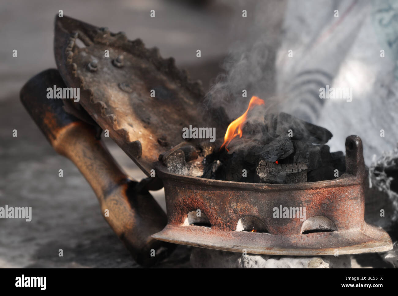 Un dhobi prépare un vieux charbon de fer à repasser. Après les charbons sont prêts, les sections locales apportent leur lessive à la dhobi pour le repassage. Banque D'Images