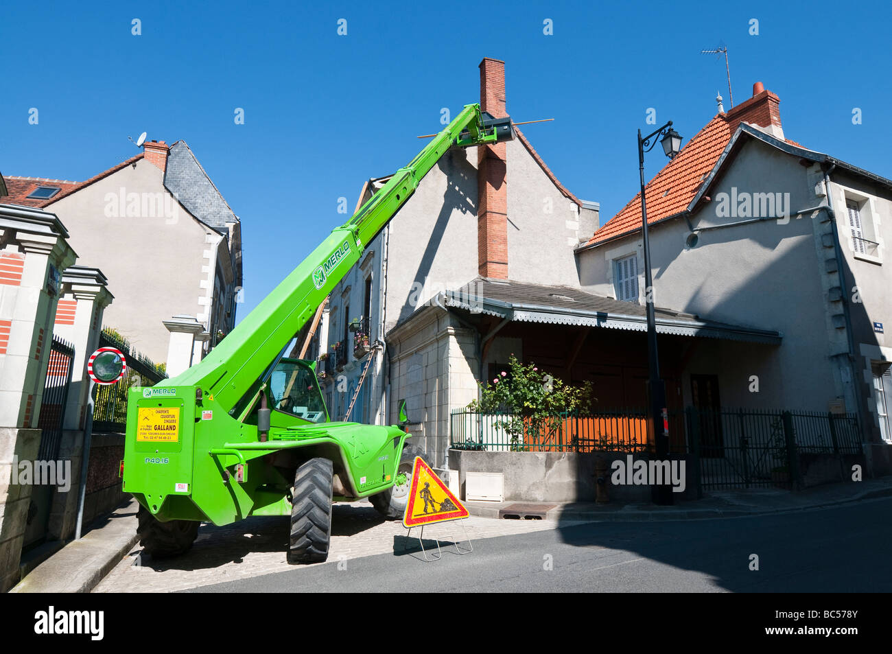 Entrepreneur en construction dans la benne de l'extension de la réparation de grue à flèche toit de maison - France. Banque D'Images