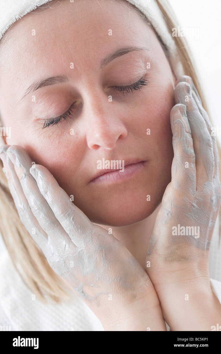 Jeune femme de mettre de la crème sur son visage - Banque D'Images
