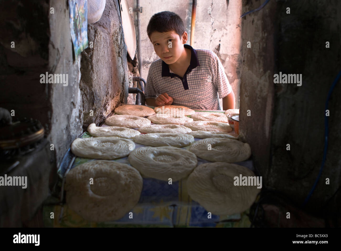 Une visite d'une boulangerie locale en Ouzbékistan, l'Asie centrale : Jeune garçon et pain traditionnel (Naan, Nan, Non, Nun) dans un four. Banque D'Images