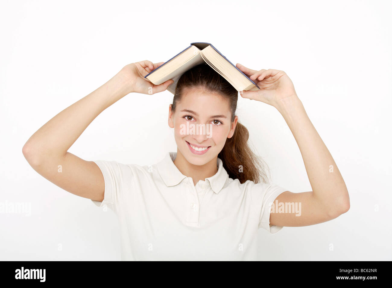 Jeune femme ((16-17) holding book over head Banque D'Images