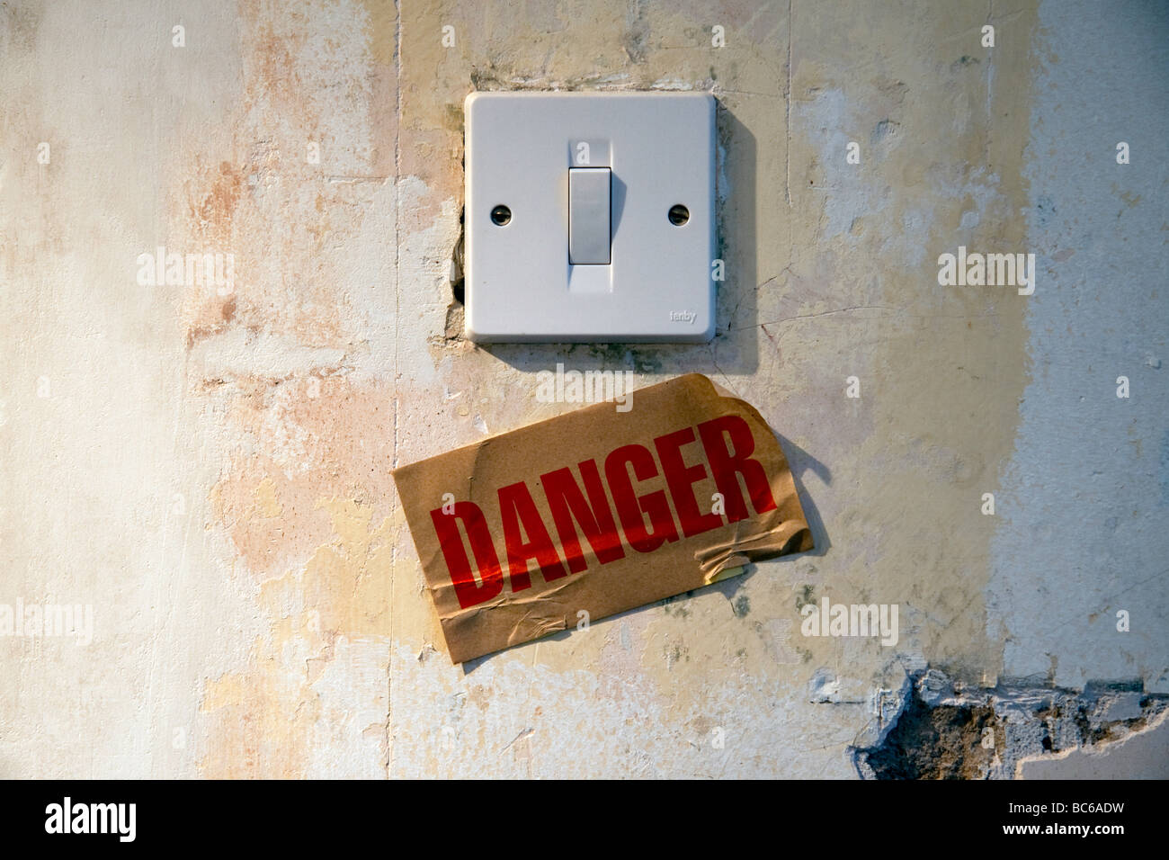 Une fiesta sur un mur délabré avec un signe sous la lecture de "danger". Banque D'Images